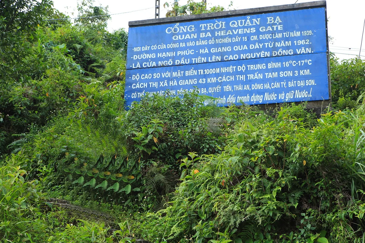 A blue signboard for Quan Ba Heavens Gate stands amid lush greenery in Ha Giang province.