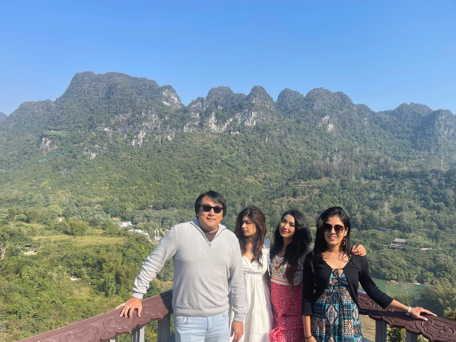 Four visitors pose on a viewing platform overlooking jagged limestone peaks and green valleys near Cao Bang.