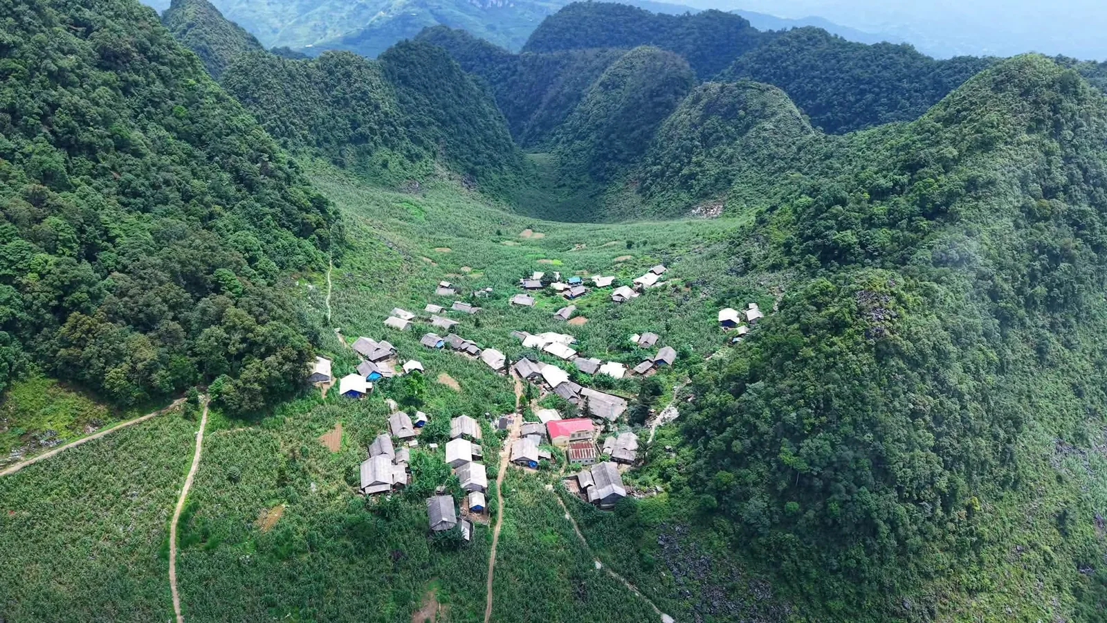 Aerial view of a small village nestled in a green valley surrounded by limestone mountains in Ha Giang.