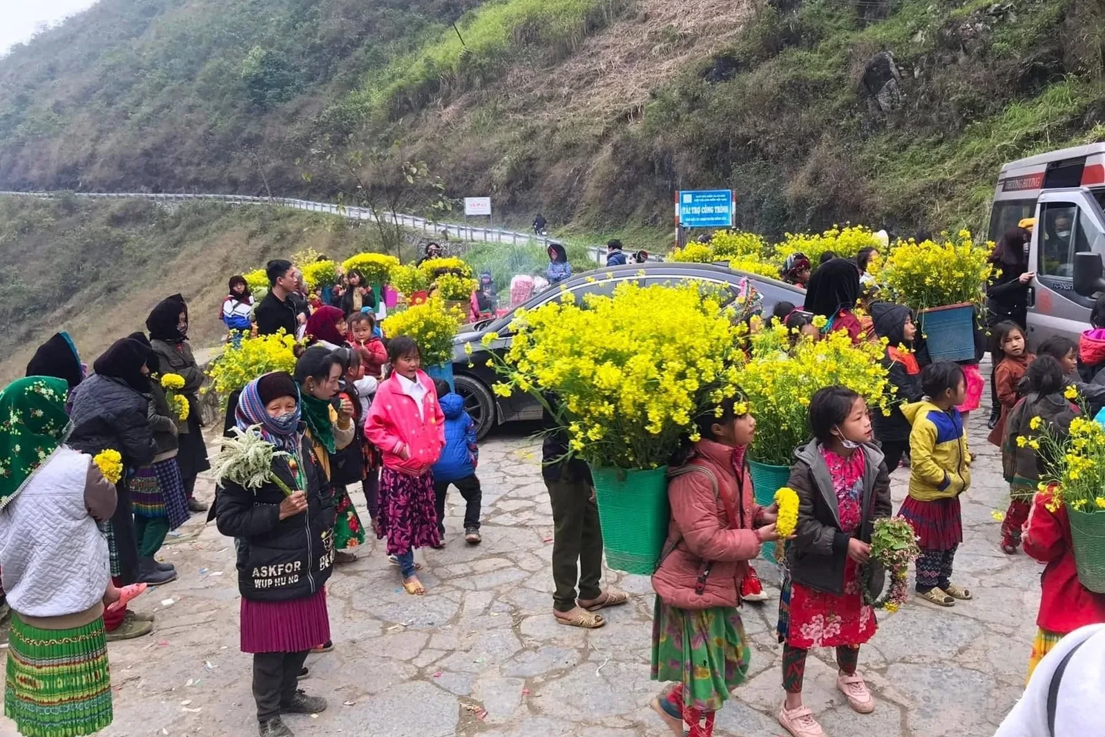 Local vendors sell bright yellow flower baskets to visitors along a mountain road on the Ha Giang Loop.