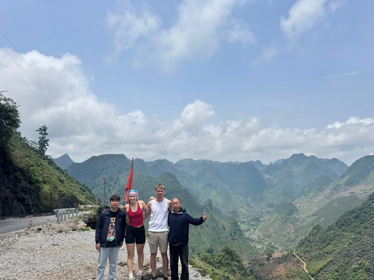 Travelers pose at a mountain viewpoint overlooking the layered limestone peaks of the Ha Giang Loop.